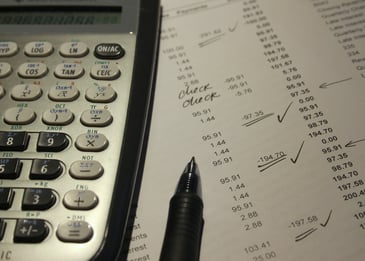 a calculator, pen, and financial statement with markups